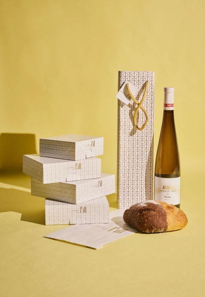 Emballages sur-mesure pour l’Auberge de l’Ill, incluant un sac pour les bouteilles de vin, une boîte pour les pâtisseries et un sac en papier pour le pain, conçus par Schneider Packaging.