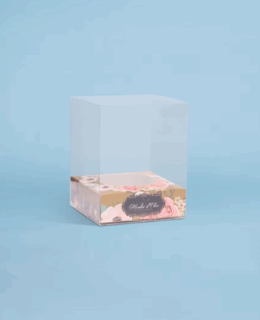 Boîte moulage transparente personnalisée avec socle personnalisable, mettant en valeur des moules en chocolat tels que poules, œufs et autres créations gourmandes, pour une présentation élégante.